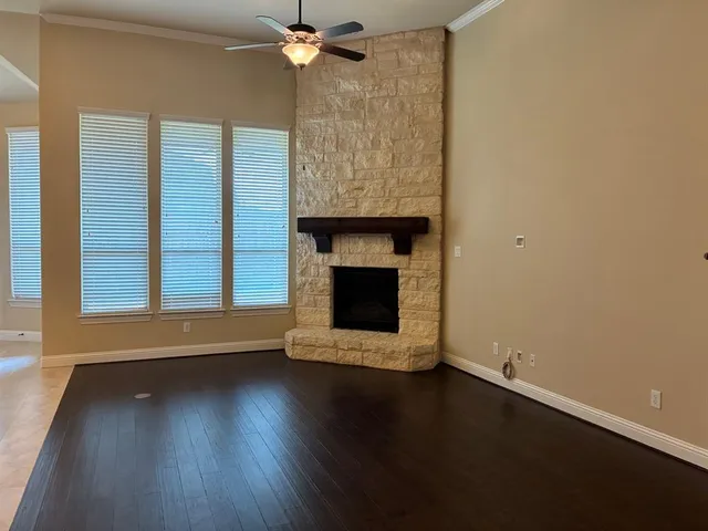 an empty room with wooden floor fan and windows