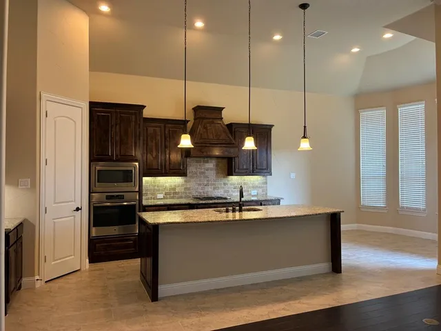 a kitchen with kitchen island granite countertop a stove a sink and a refrigerator
