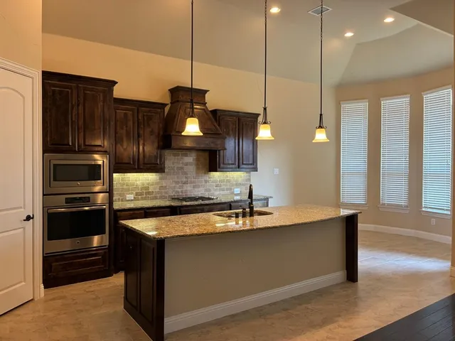a kitchen with kitchen island granite countertop a sink a counter space appliances and cabinets