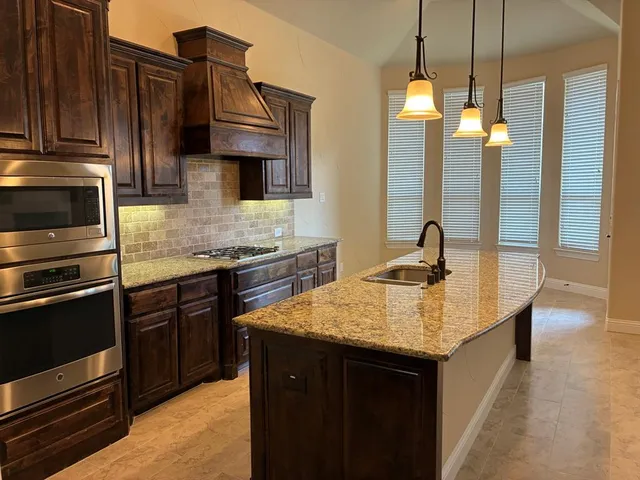 a kitchen with stainless steel appliances granite countertop a sink wooden cabinets and a stove