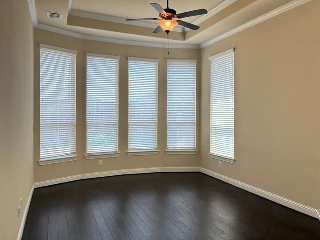 an empty room with wooden floor fan and windows