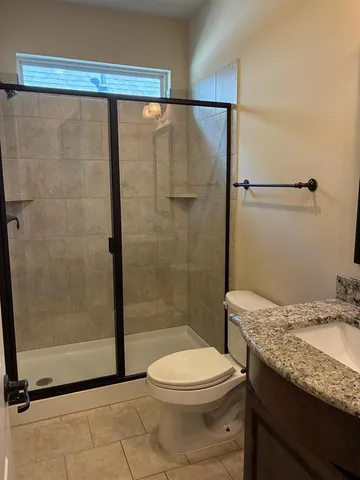 a bathroom with a granite countertop bathtub shower sink mirror and toilet