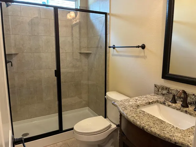 a bathroom with a granite countertop sink toilet and shower