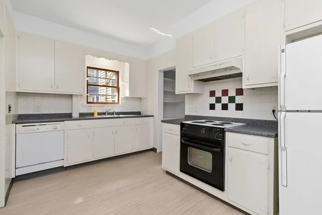 a kitchen with granite countertop white cabinets and white appliances