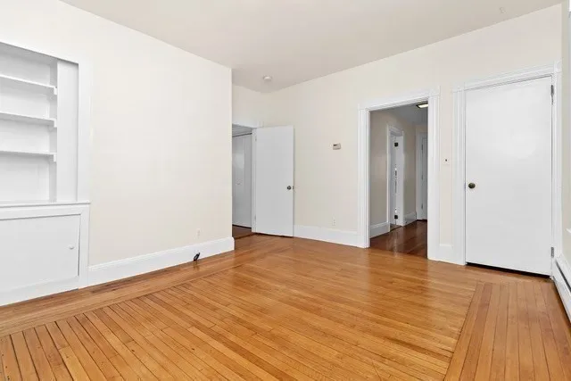 a view of an empty room with wooden floor and closet