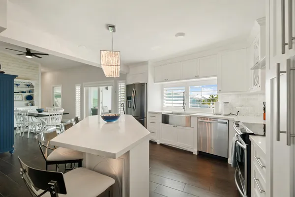 a kitchen with stainless steel appliances a dining table chairs and refrigerator