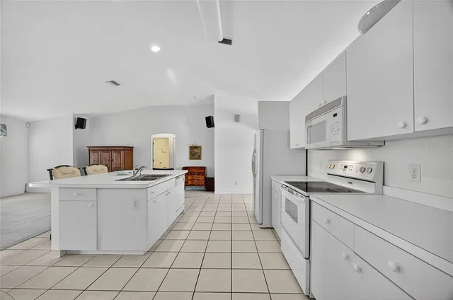 a kitchen that has a lot of white cabinets and stainless steel appliances