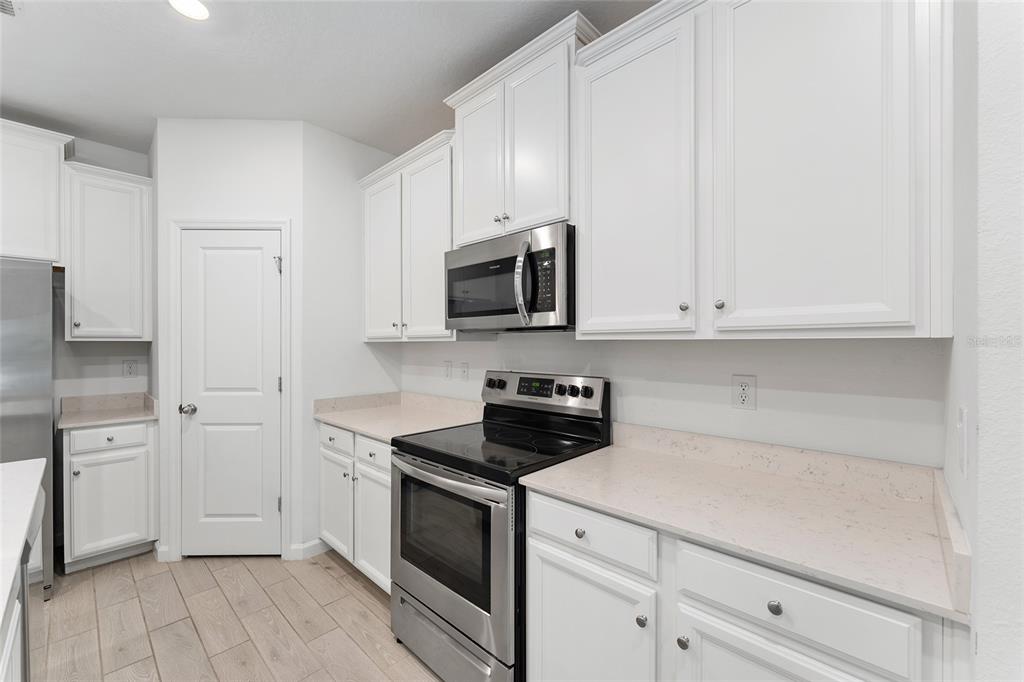 7755 Southwest 74th Loop Ocala, FL 34481 - Photo 11 of 66 a kitchen with white cabinets and stainless steel appliances