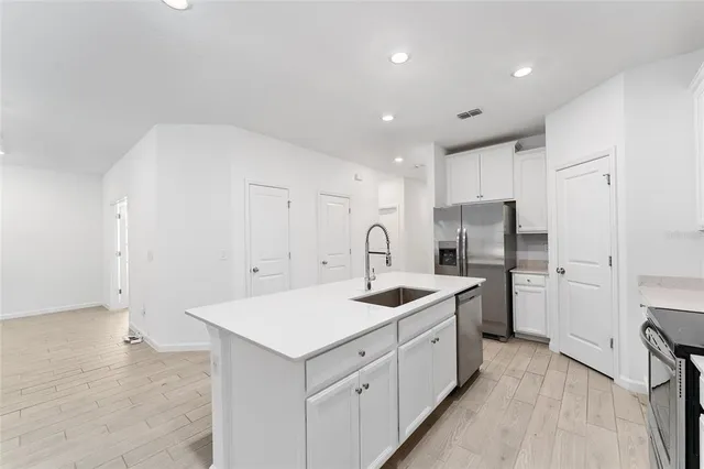 a kitchen with kitchen island a sink dishwasher a stove and a refrigerator with wooden floor