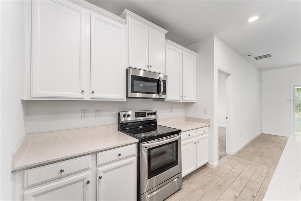 7755 Southwest 74th Loop Ocala, FL 34481 - Photo 15 of 66 a kitchen with white cabinets and stainless steel appliances