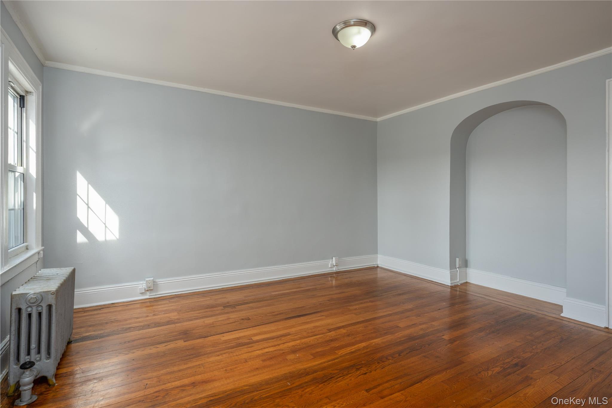 179-65 Selover Road Queens, NY 11434 - Photo 19 of 33 Primary Bedroom12'3" × 13'6" featuring wood-finish flooring, a double-hung window, and an arched wall niche