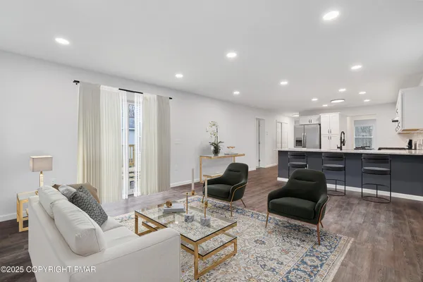 a living room with furniture wooden floor and kitchen view