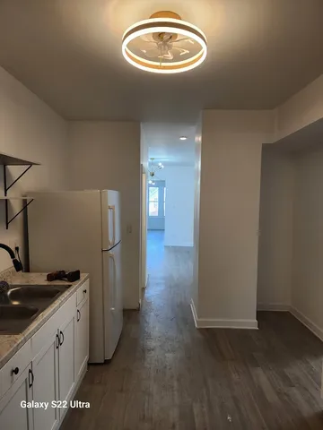 a view of a kitchen with refrigerator and wooden floor