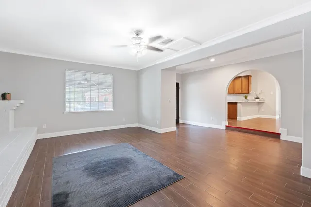 an empty room with wooden floor chandelier fan and windows