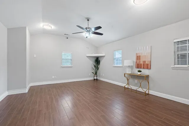 a view of an empty room with a window and wooden floor