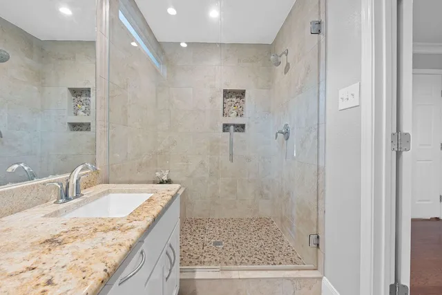 a bathroom with a granite countertop sink a mirror and shower