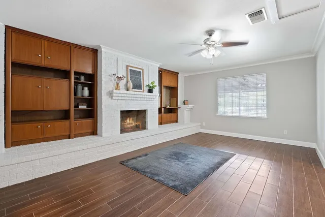 a view of an empty room with wooden floor fireplace and a window