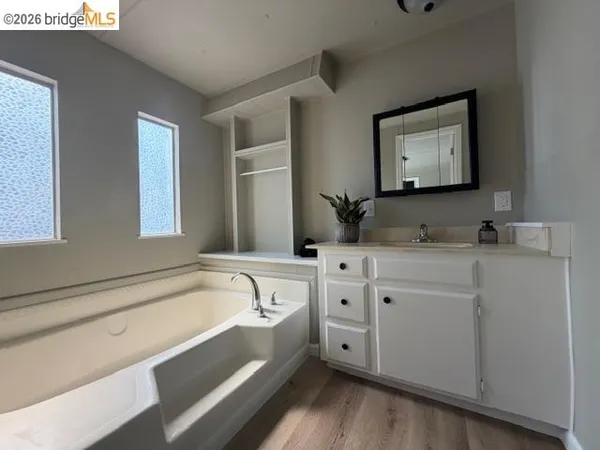 a bathroom with a granite countertop tub sink and mirror