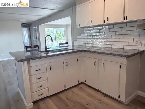 a kitchen with granite countertop white cabinets and a sink