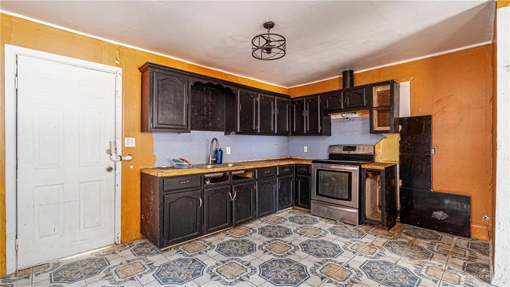 610 West Pike Boulevard Weslaco, TX 78596 - Photo 11 of 15 Kitchen with stainless steel electric range oven and dark wood finish cabinetry