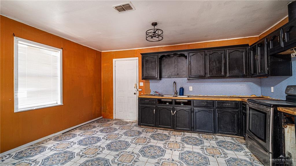 610 West Pike Boulevard Weslaco, TX 78596 - Photo 10 of 15 Kitchen featuring stainless steel electric range oven, dark cabinets, and wood walls