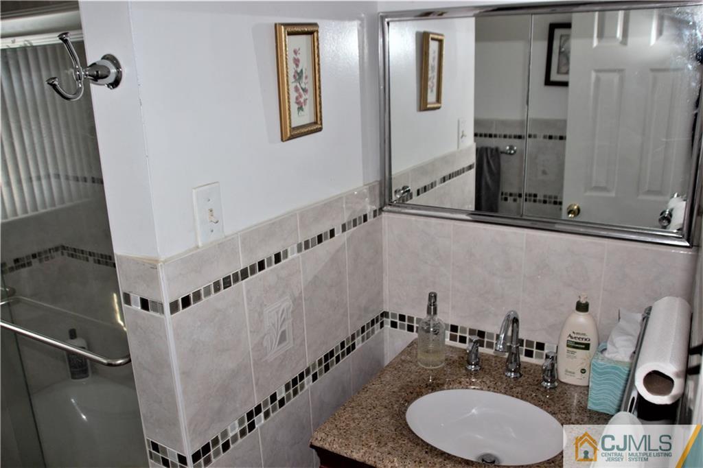 75 Rodak Circle Edison, NJ 08817 - Photo 17 of 32 a bathroom with a granite countertop sink a mirror and shower