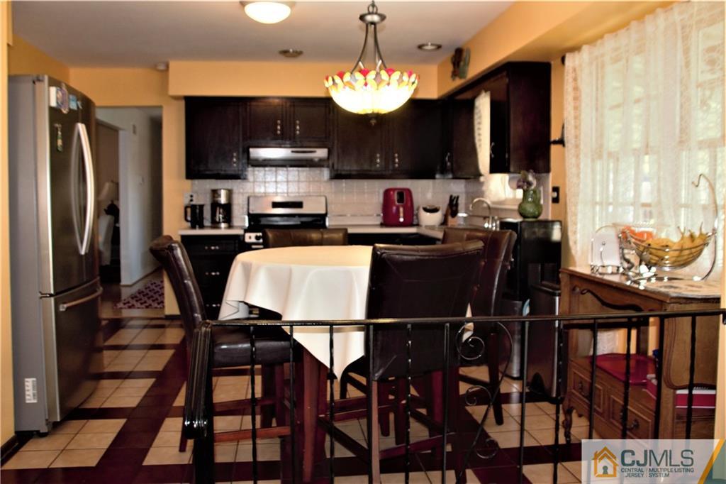 75 Rodak Circle Edison, NJ 08817 - Photo 9 of 32 a kitchen with a table chairs refrigerator and microwave