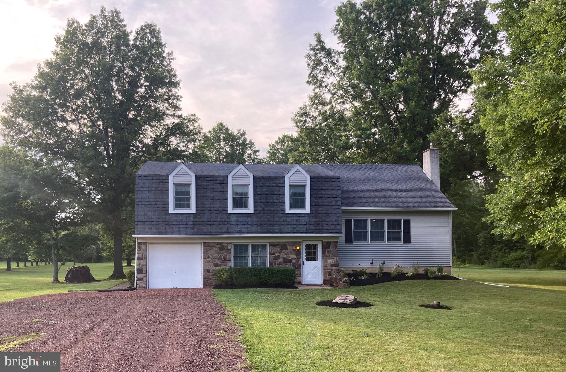 a front view of a house with a garden and trees