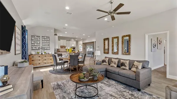 a living room with furniture a clock on wall and a flat screen tv