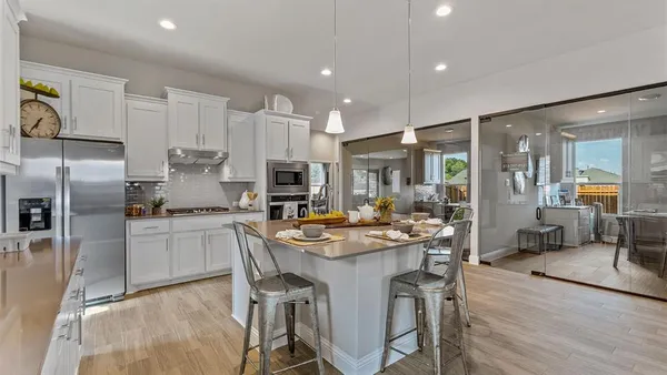 a kitchen with stainless steel appliances a sink a stove a refrigerator cabinets and living room view