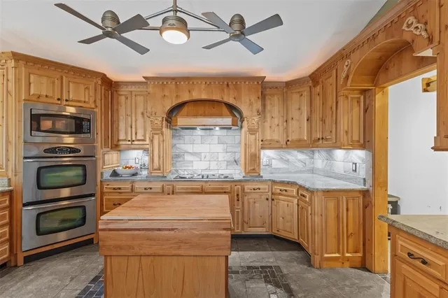 a kitchen with stainless steel appliances granite countertop a sink a stove and a refrigerator