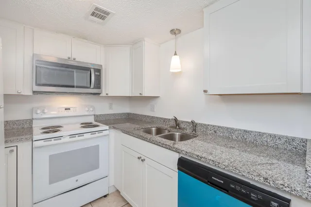 a kitchen with granite countertop white cabinets and a stove top oven