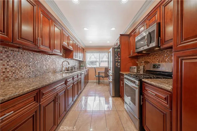 a kitchen with stainless steel appliances granite countertop a stove top oven a sink dishwasher and cabinets with wooden floor