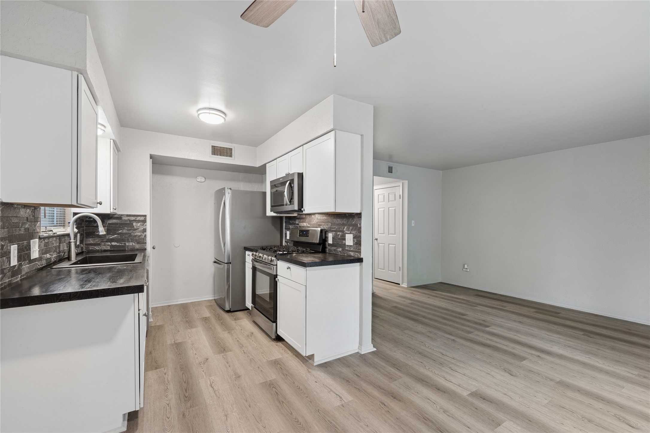 820 Sahara Avenue, Unit B Austin, TX 78745 - Photo 26 of 29 Kitchen featuring dark countertops, stainless steel appliances, white cabinets, and ceiling fan