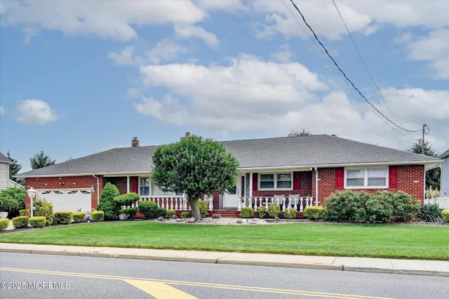 a front view of a house with a yard and trees