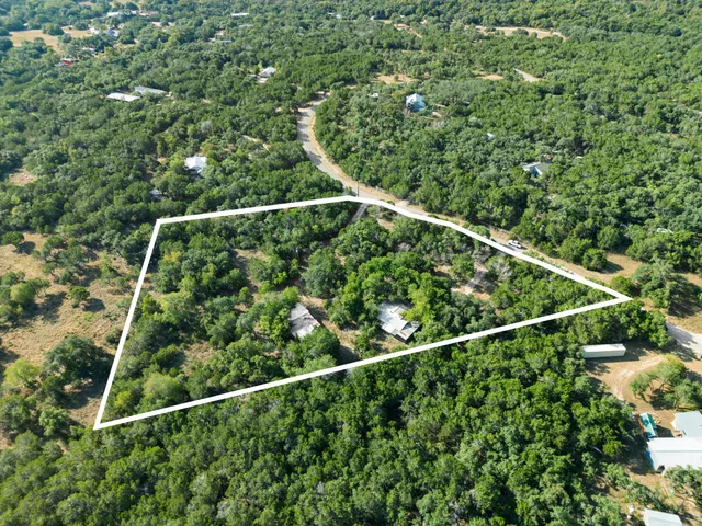an aerial view of residential houses with outdoor space and trees