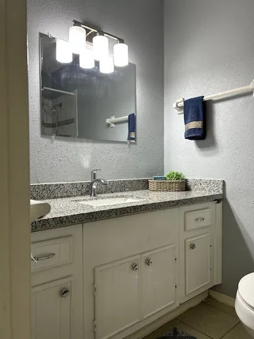 a bathroom with a granite countertop sink a large mirror and a toilet