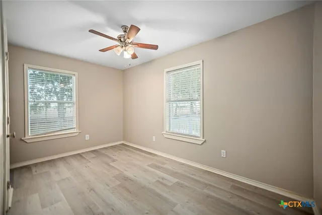 an empty room with windows and fan