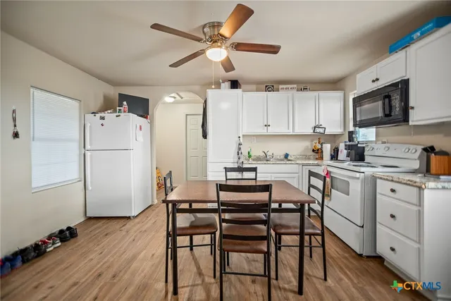 a kitchen with a refrigerator a white table and chairs
