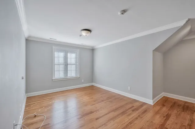 a view of an empty room with wooden floor and a ceiling fan