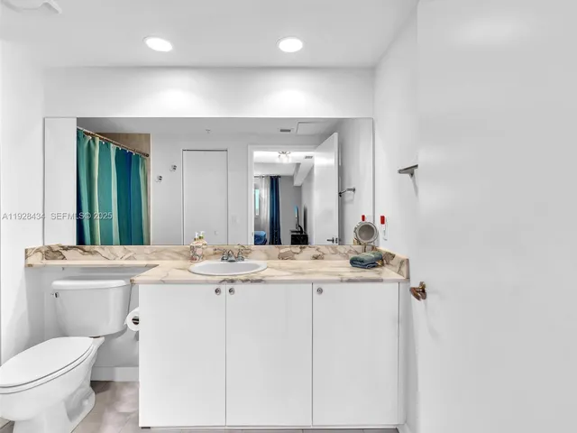 a bathroom with a granite countertop sink toilet a mirror and shower