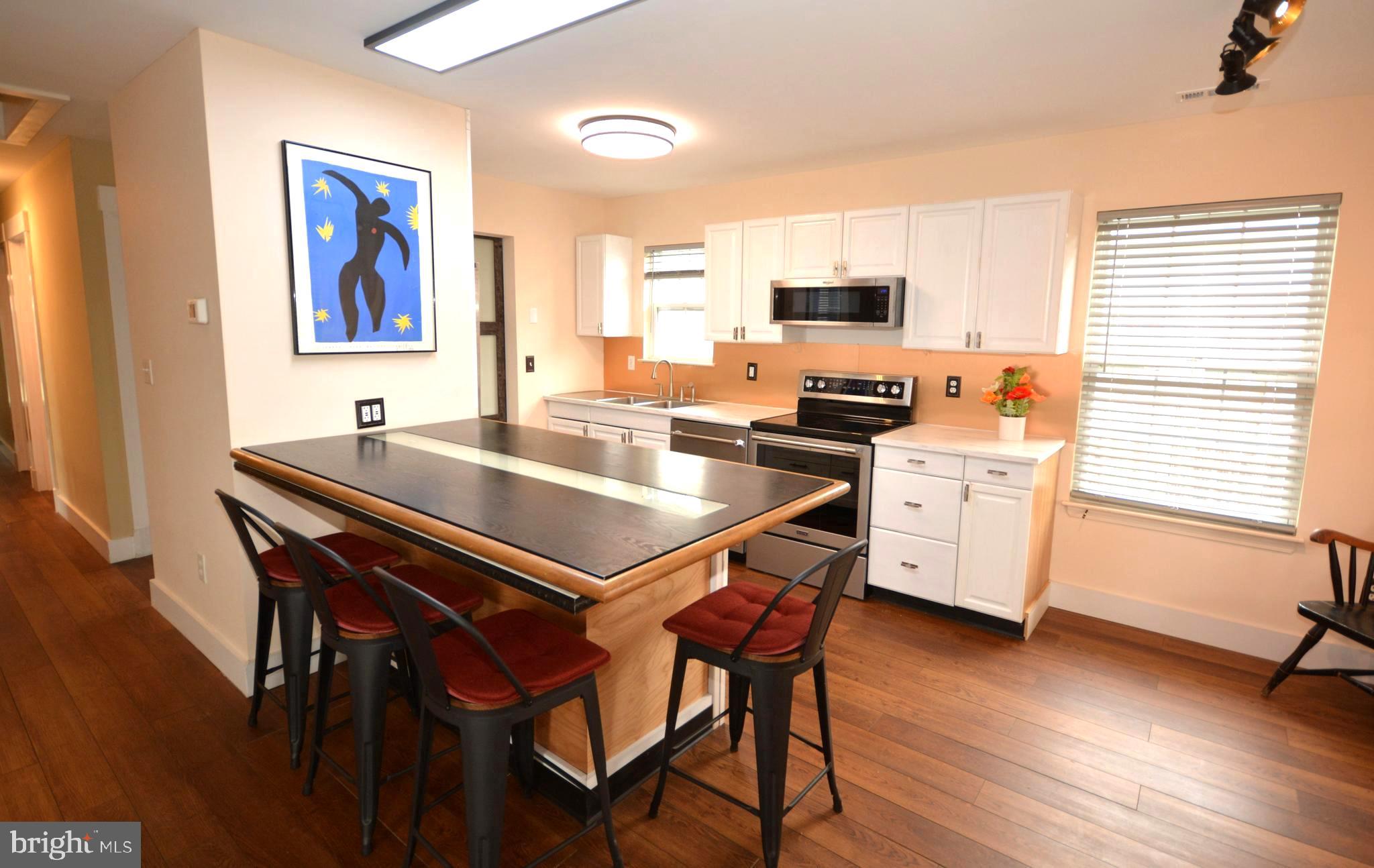 106 B Conner Street St. Michaels, MD 21663 - Photo 9 of 27 a kitchen with stainless steel appliances stove microwave and wooden floor