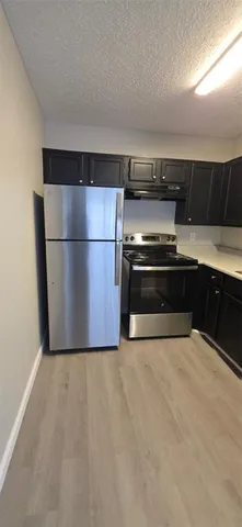a view of kitchen with stainless steel appliances wooden floor and chair
