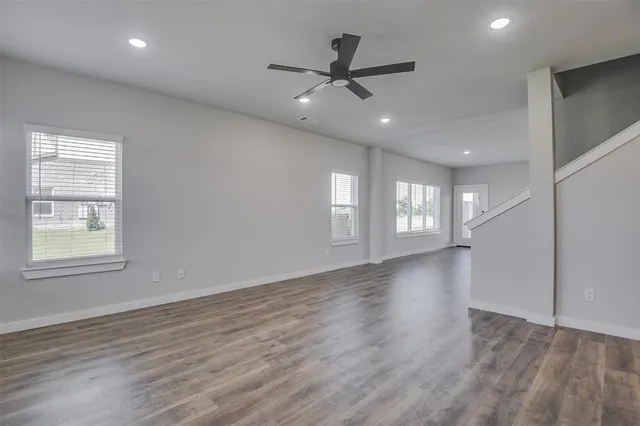 a view of an empty room with a window and wooden floor