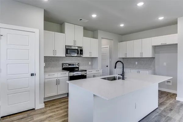 a kitchen with kitchen island white cabinets and stainless steel appliances