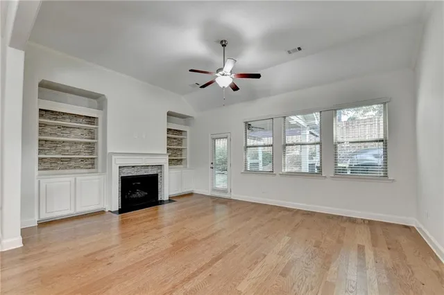 a view of a livingroom with a fireplace a ceiling fan and windows