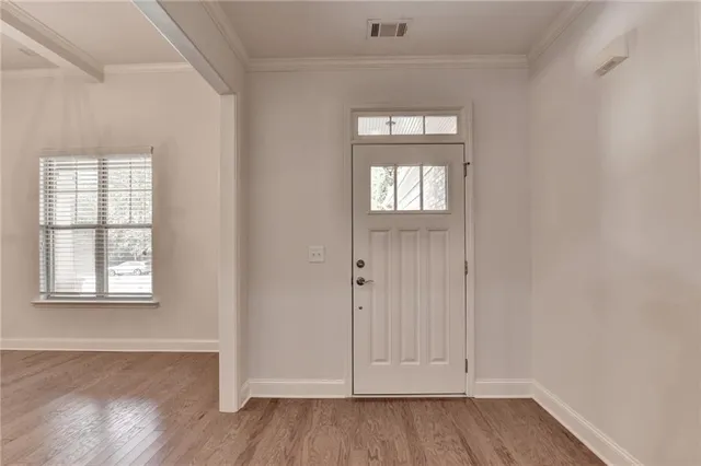 an empty room with wooden floor closet and windows