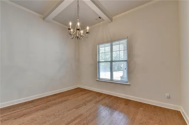 an empty room with wooden floor chandelier fan and windows