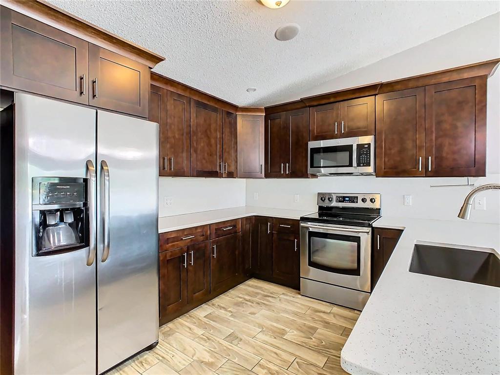 3194 Windmill Point Boulevard Kissimmee, FL 34746 - Photo 11 of 32 a kitchen with granite countertop a refrigerator stove and microwave