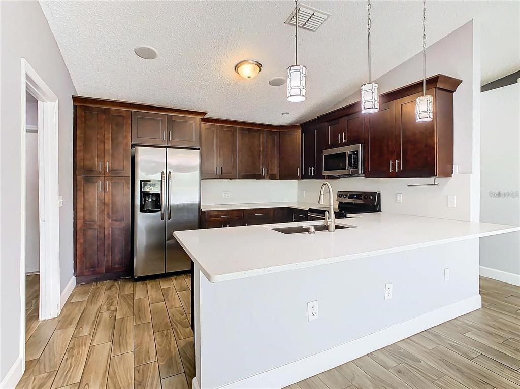 3194 Windmill Point Boulevard Kissimmee, FL 34746 - Photo 8 of 32 a kitchen with kitchen island a sink stainless steel appliances and cabinets